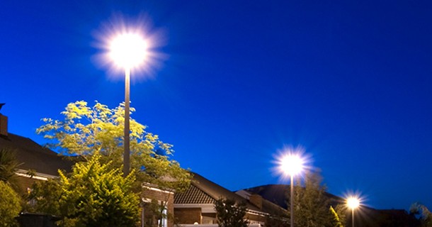 Three lamp posts lit bright in the night of a neighborhood
